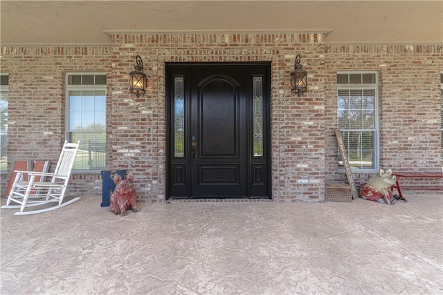 doorway to property featuring brick siding and covered porch
