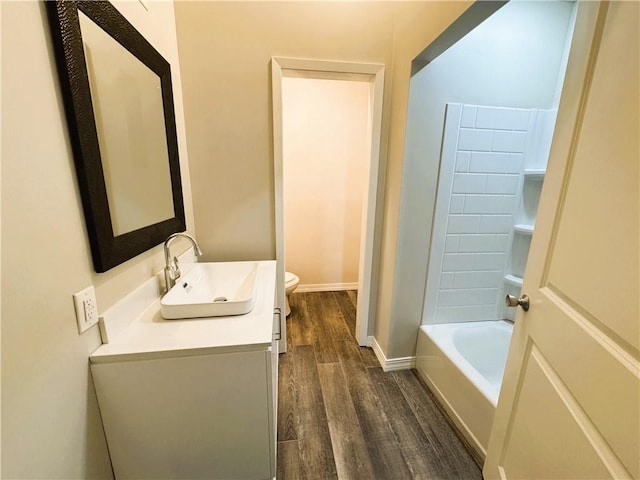 bathroom with wood finished floors, vanity, toilet, and baseboards