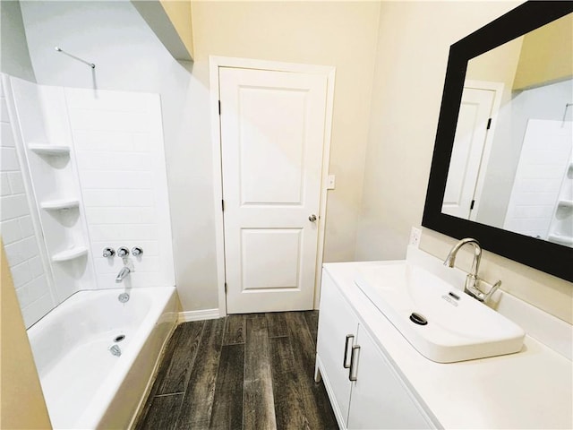 full bath with baseboards, wood finished floors, vanity, and bathing tub / shower combination