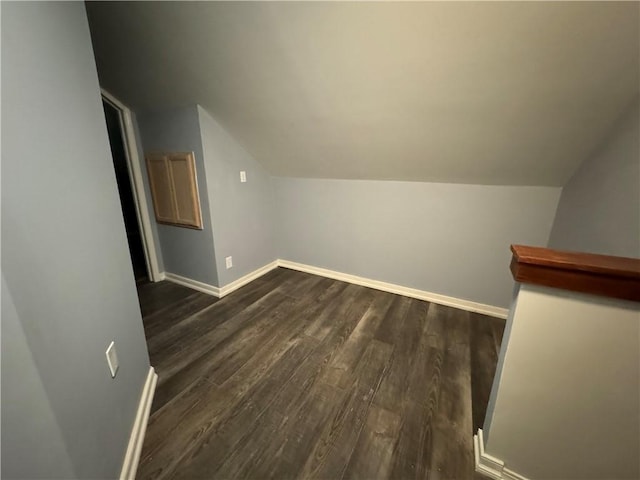 additional living space with vaulted ceiling, baseboards, and dark wood-style floors