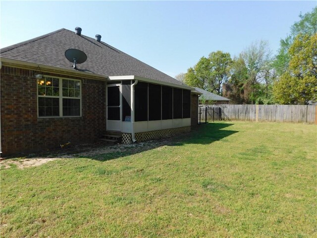 back of house with a lawn, a fenced backyard, brick siding, roof with shingles, and a sunroom