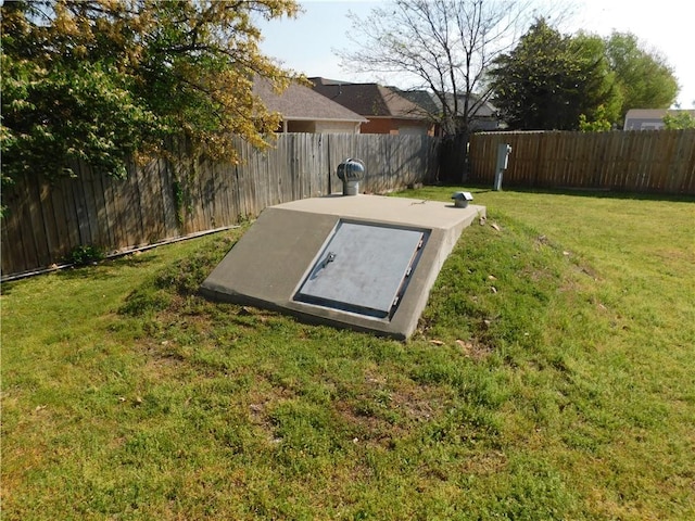 view of storm shelter with a lawn and a fenced backyard