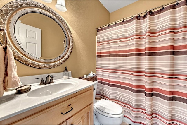 bathroom featuring a shower with curtain, a textured wall, vanity, and toilet