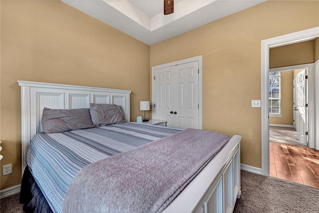 bedroom featuring dark carpet, ceiling fan, baseboards, and a closet