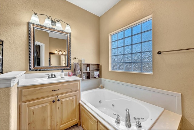 full bathroom featuring a textured wall, vanity, and a jetted tub