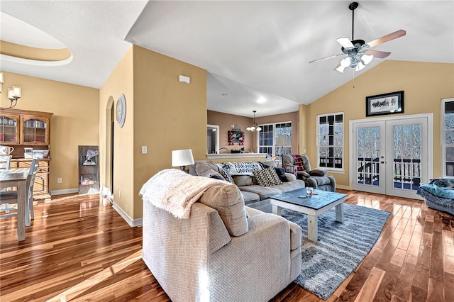 living room with wood finished floors, baseboards, and ceiling fan with notable chandelier