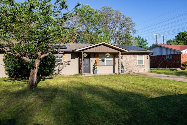 ranch-style house featuring roof mounted solar panels and a front lawn