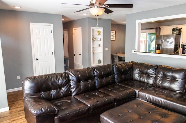 living room with baseboards, ceiling fan, wood finished floors, and built in shelves