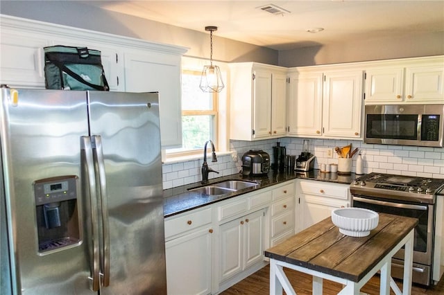 kitchen featuring visible vents, white cabinets, tasteful backsplash, a sink, and stainless steel appliances