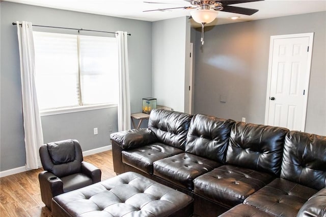 living area featuring baseboards, a ceiling fan, and light wood-style flooring