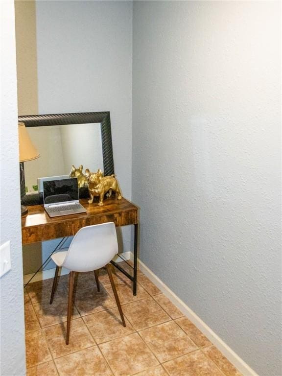 home office with light tile patterned flooring, baseboards, and a textured wall