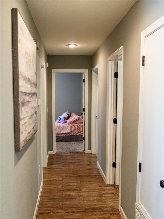 hallway featuring baseboards and dark wood-type flooring