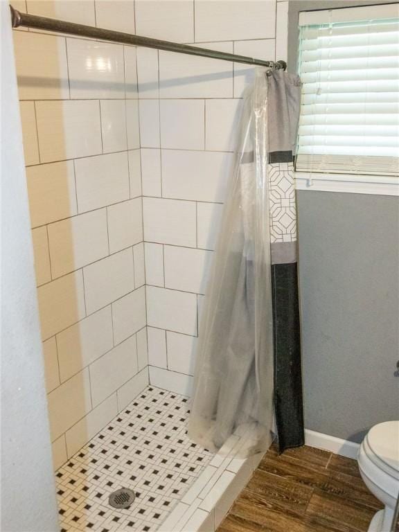 full bath featuring a stall shower, toilet, and wood finished floors