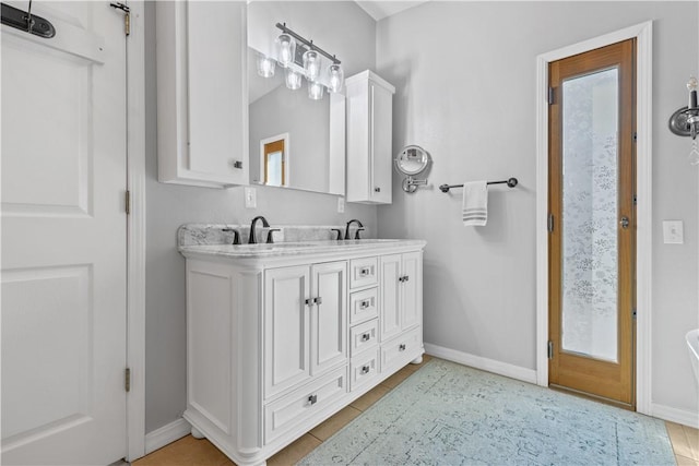 full bathroom featuring double vanity, tile patterned flooring, baseboards, and a sink