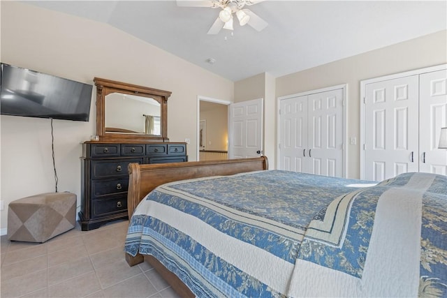bedroom with lofted ceiling, multiple closets, tile patterned flooring, and a ceiling fan