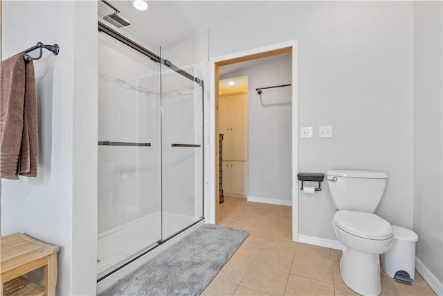 bathroom with a shower stall, toilet, tile patterned floors, and baseboards