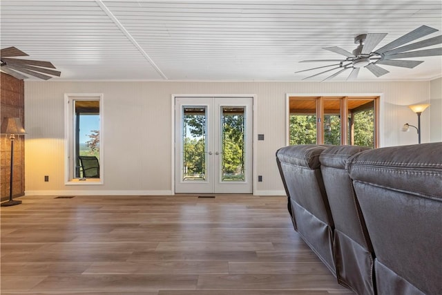 living room featuring wood finished floors, a healthy amount of sunlight, a ceiling fan, and baseboards
