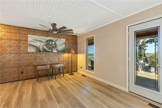 unfurnished room with wood finished floors, visible vents, wood walls, and ceiling fan