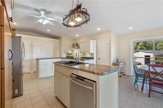 kitchen with dark countertops, appliances with stainless steel finishes, light tile patterned floors, and a sink