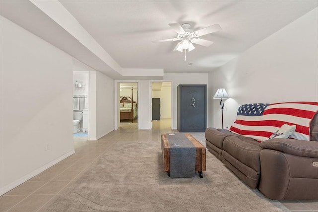living room with a ceiling fan, baseboards, and light tile patterned flooring