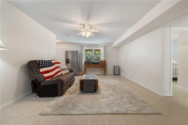 living room featuring light tile patterned floors, baseboards, and ceiling fan