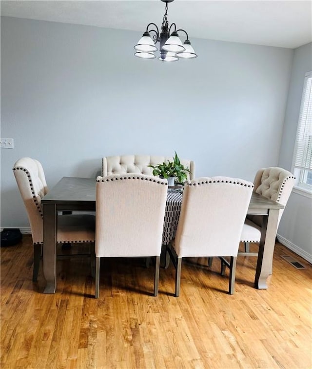 dining room featuring baseboards, light wood-style flooring, visible vents, and an inviting chandelier