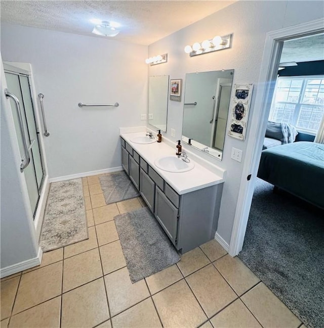 full bathroom featuring tile patterned flooring, a sink, a textured ceiling, and a stall shower