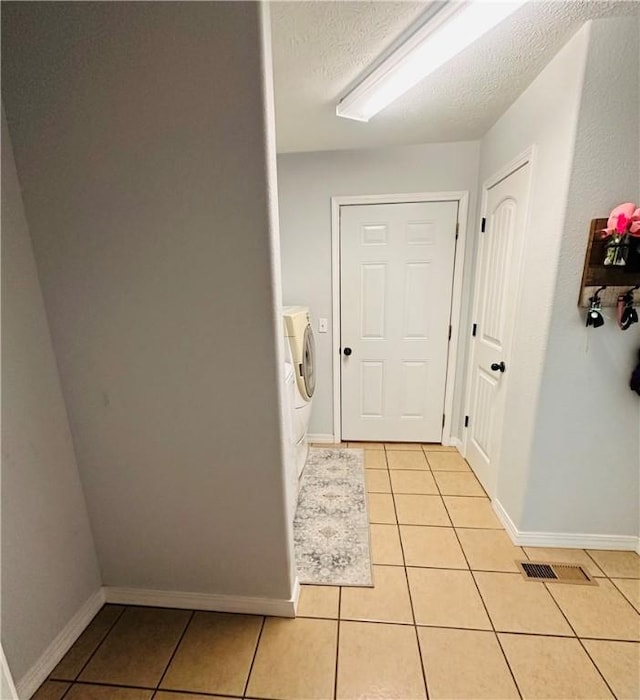 interior space with baseboards, a textured ceiling, and light tile patterned floors