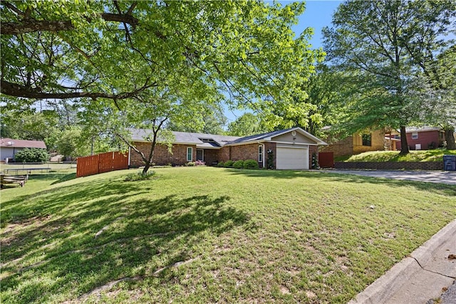 single story home with an attached garage, fence, a front yard, and brick siding