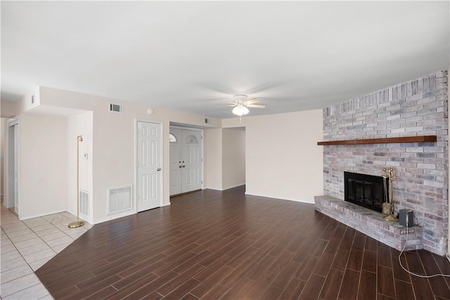 unfurnished living room with a ceiling fan, wood finished floors, visible vents, and a fireplace