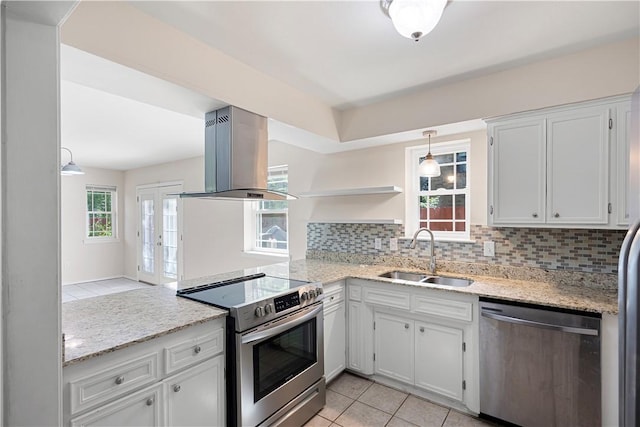 kitchen with island exhaust hood, appliances with stainless steel finishes, tasteful backsplash, and a sink