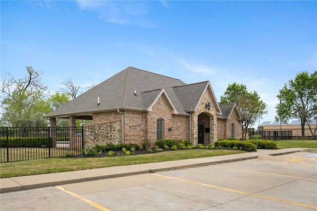 exterior space featuring brick siding, a shingled roof, uncovered parking, and fence
