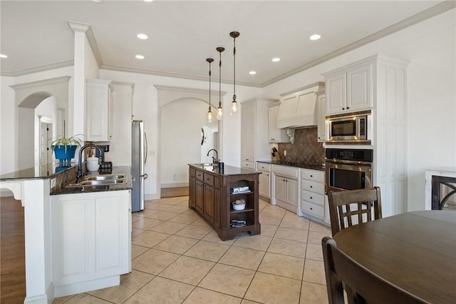 kitchen featuring decorative backsplash, stainless steel appliances, arched walkways, and a sink