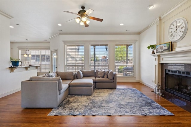 living area with a tiled fireplace, baseboards, a ceiling fan, wood finished floors, and ornamental molding