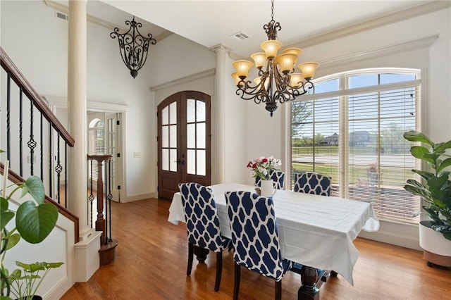dining room featuring baseboards, visible vents, a chandelier, wood finished floors, and stairway