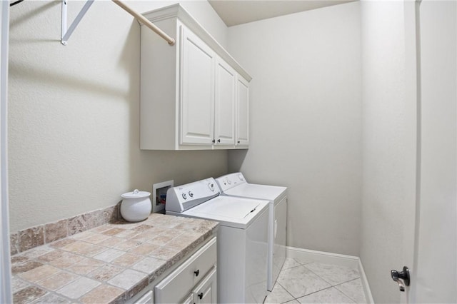 clothes washing area featuring baseboards, washer and clothes dryer, and cabinet space