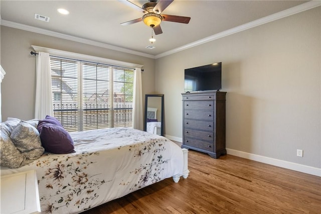 bedroom with baseboards, ornamental molding, wood finished floors, and visible vents