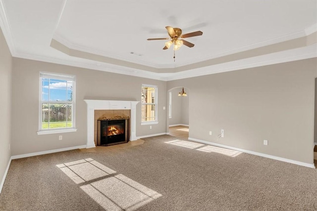 unfurnished living room featuring a fireplace, ornamental molding, carpet, and a raised ceiling