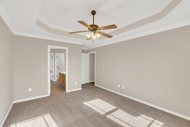 unfurnished bedroom featuring light carpet, crown molding, a tray ceiling, and baseboards