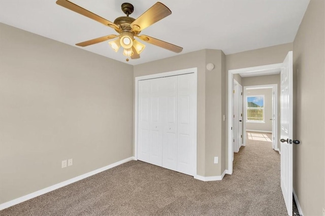 unfurnished bedroom with a closet, carpet flooring, baseboards, and a ceiling fan