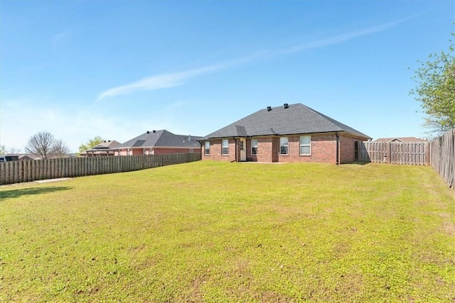 rear view of property with a lawn, brick siding, and a fenced backyard