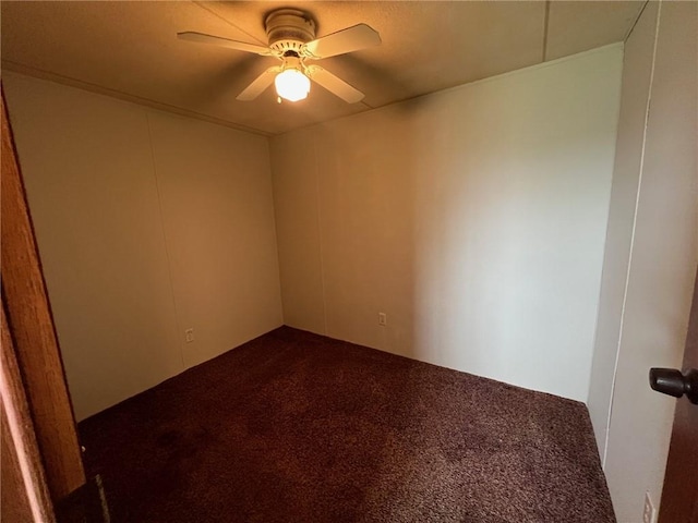 spare room with dark carpet and ceiling fan