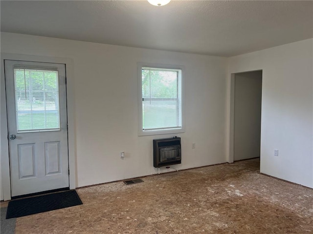 unfurnished living room featuring a healthy amount of sunlight, heating unit, and visible vents