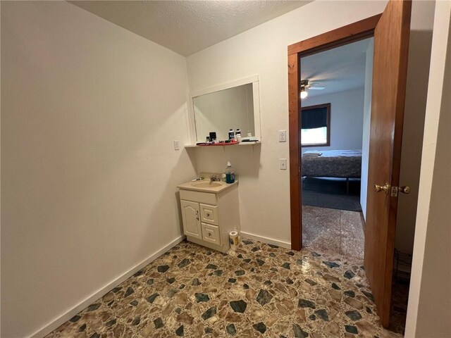 corridor with baseboards, a sink, stone flooring, and a textured ceiling
