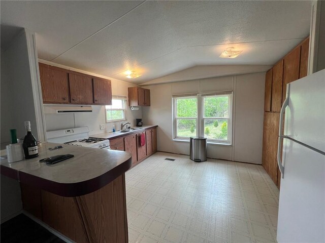 kitchen with exhaust hood, light floors, vaulted ceiling, white appliances, and a peninsula
