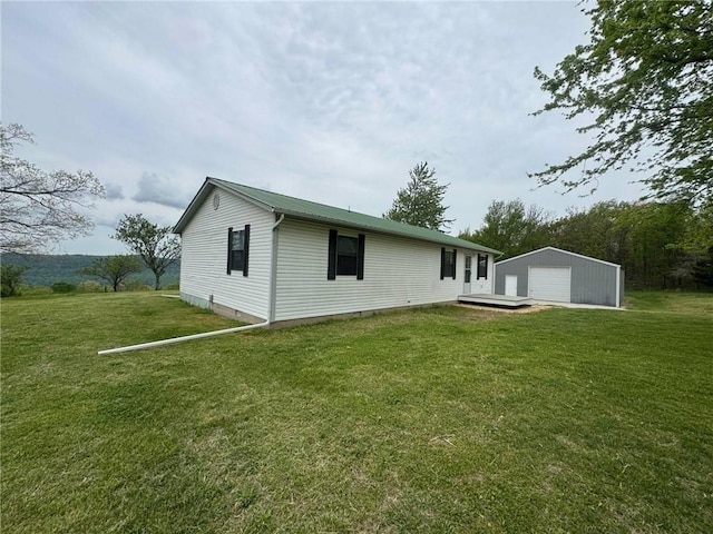 back of property featuring a garage, a yard, and an outdoor structure