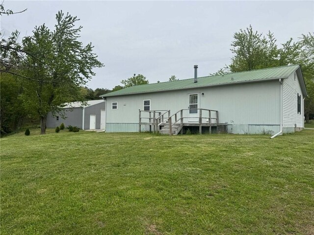 back of property with a yard, metal roof, and a deck