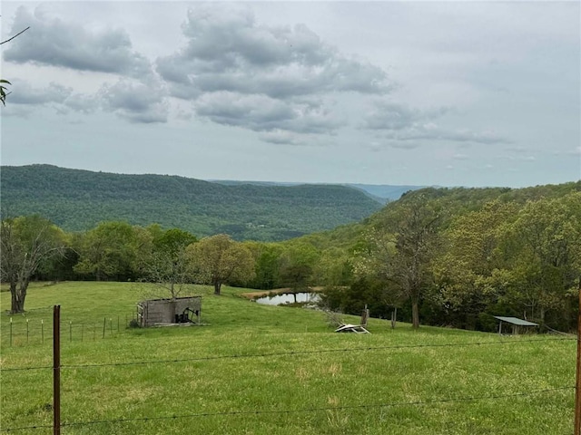 surrounding community featuring fence, a water and mountain view, a rural view, a view of trees, and a yard