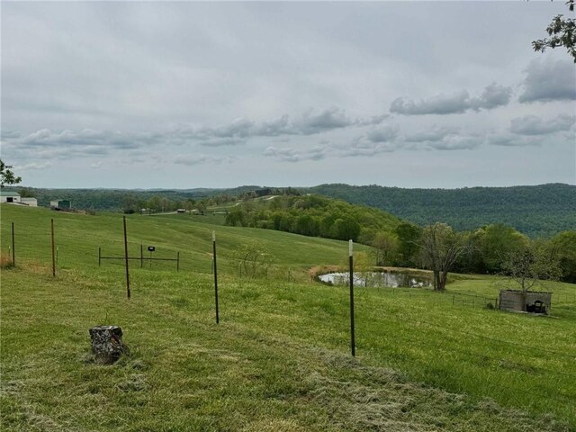 view of home's community featuring fence, a lawn, and a rural view
