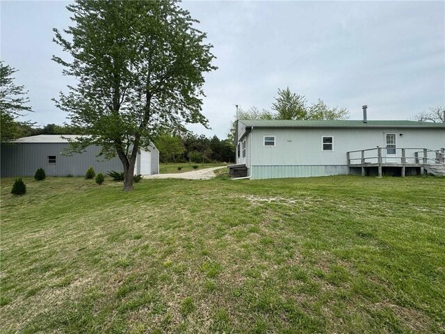 view of yard featuring a wooden deck, a detached garage, an outdoor structure, and central AC